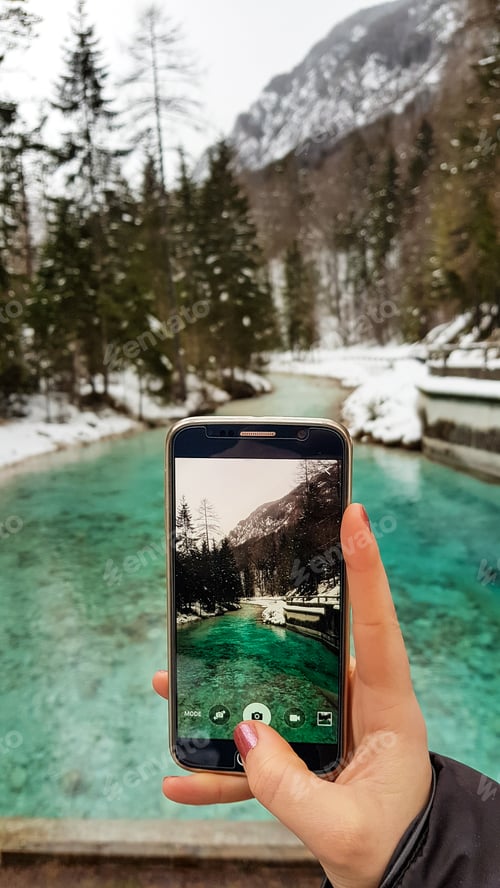 Preview: Personal perspective of woman holding mobile phone, taking photos of river and valley in mountains