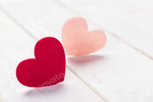 Preview: Two paper hearts in red and pink on a wooden surface during daytime