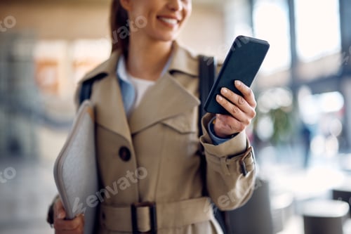Preview: Close-up of businesswoman text messaging on cell phone at train station terminal.