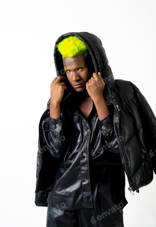Preview: Black ethnic man in studio with white background, LGTBI concept, posed with leather jacket hat