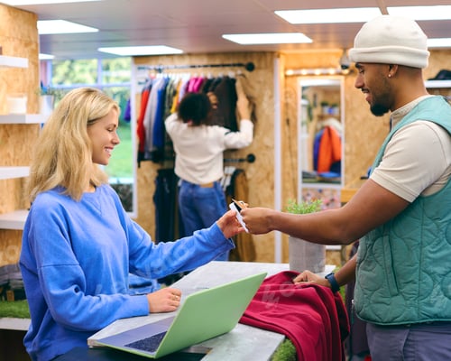 Preview: Male Customer Paying Female Sales Assistant In Fashion Store Using Contactless Payment With Card
