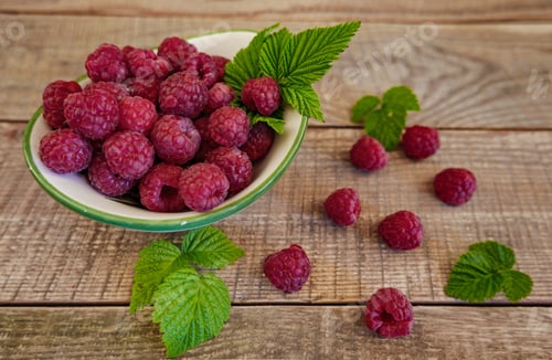 Preview: Close-up image of a bowl of raspberries on a wooden background.