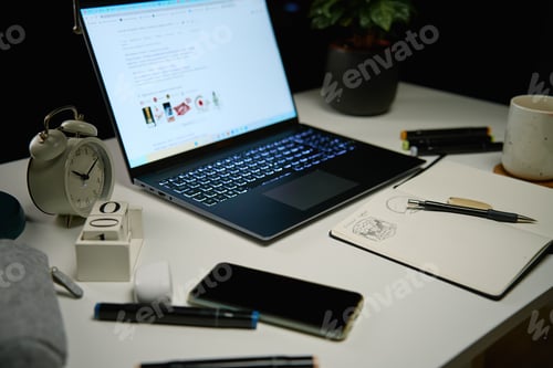 Preview: Home office workplace without people at night. Laptop on table in living room