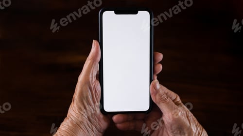 Preview: Old woman at home using a mobile phone with white screen. Mockup device