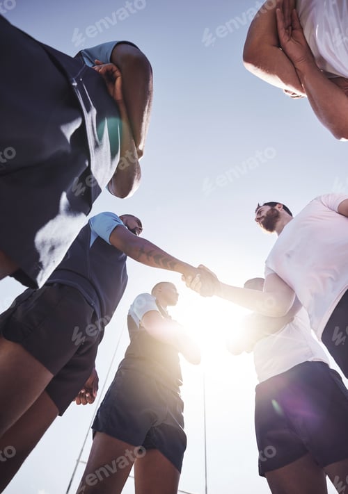 Preview: Below two opponent rugby teams shaking hands before or after a match outside on a field. Rugby play