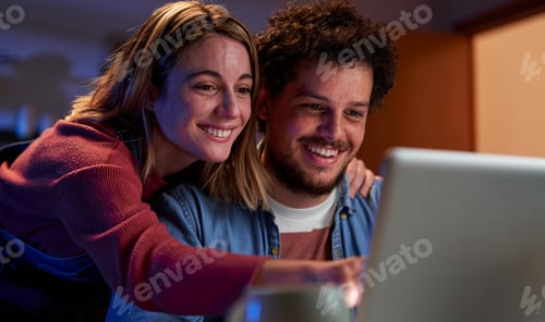 Preview: Young caucasian couple using a laptop together at home searching for a travel destination.