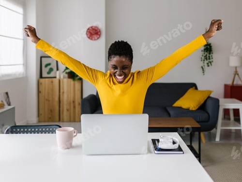 Preview: Excited Woman Celebrating Success in Home Office
