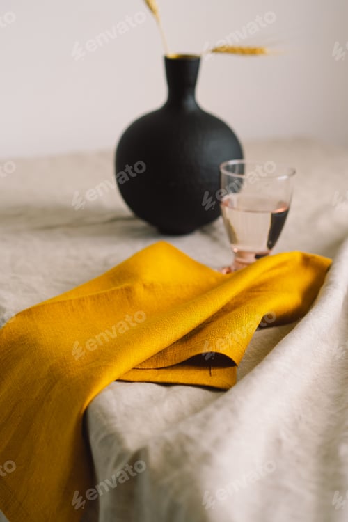 Preview: Yellow linen napkin on a tablecloth on a table.