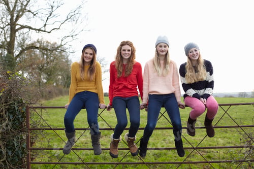 Preview: Four teenage girls sitting on gate