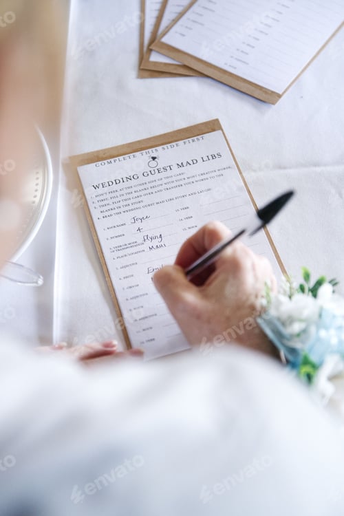 Preview: Vertical shot of a wedding guest filling out a funny mad libs party favor