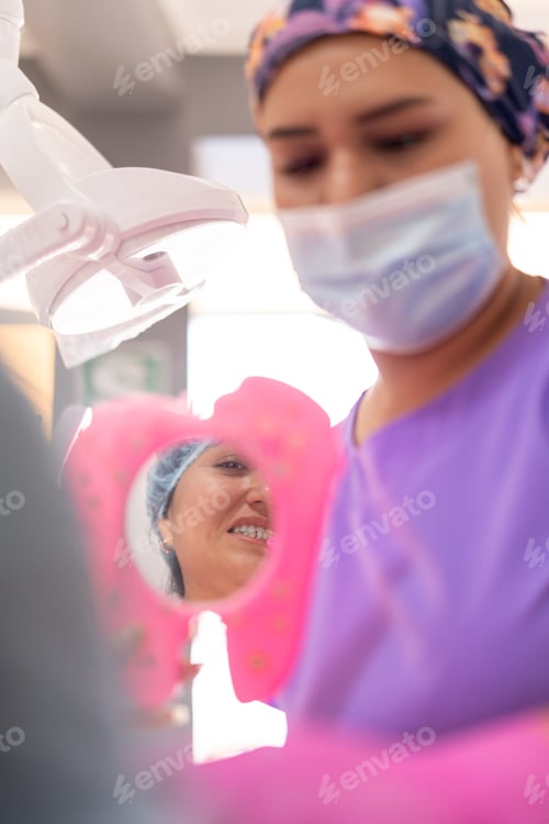 Preview: Patient checking her teeth with a mirror after her dental cleaning