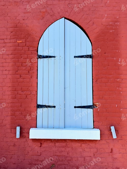 Preview: The closed blue wooden shutters of a window set in a bright red brick wall of Fisgard Lighthouse.