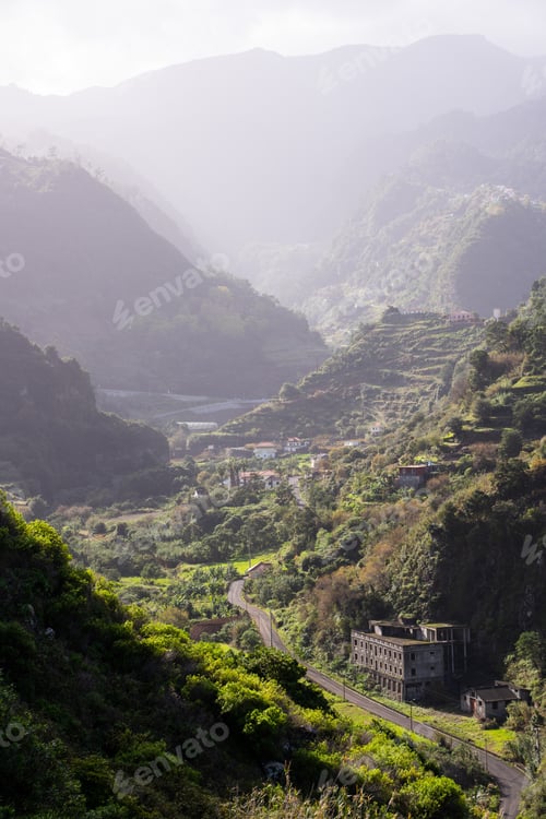 Preview: Road in the middle of a mountain range with tropical vegetation and some buildings.