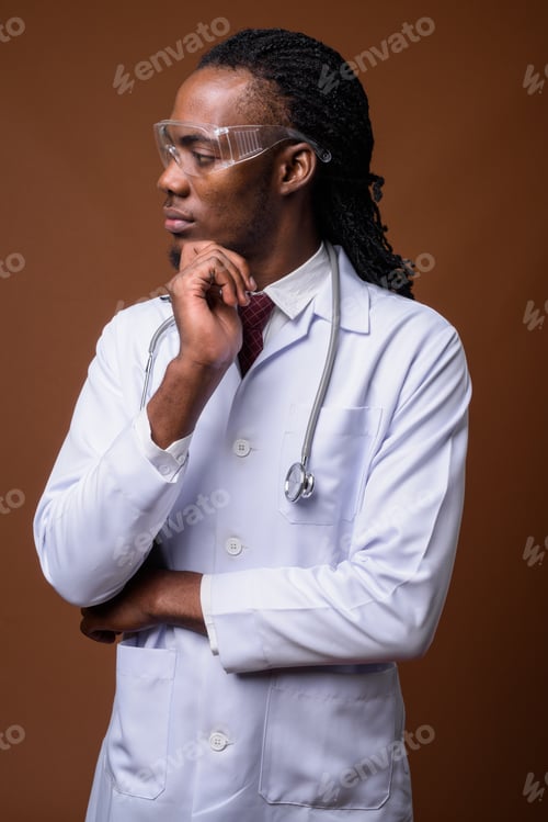 Preview: Young handsome African man doctor wearing protective glasses aga