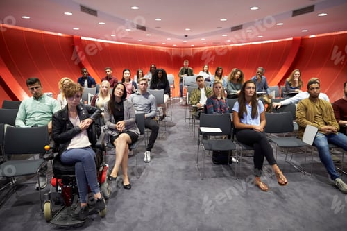 Preview: Students sit facing camera in a modern university classroom