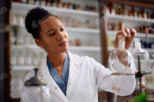 Preview: Smiling black chemist working in a pharmacy.