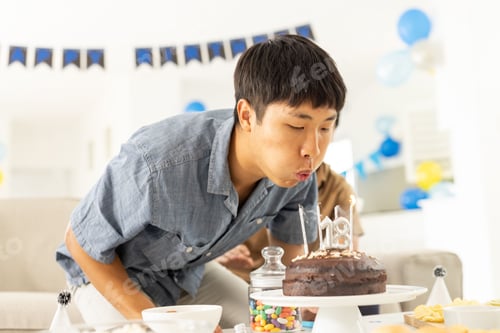 Visualização: Homem soprando velas no bolo de aniversário em casa, comemorando uma ocasião especial