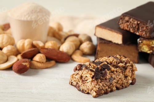 Preview: Different tasty protein bars and nuts on white table, closeup