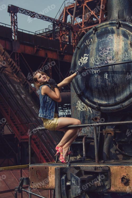 Preview: blonde sexy girl in shorts and heels at an old abandoned factory. steampunk