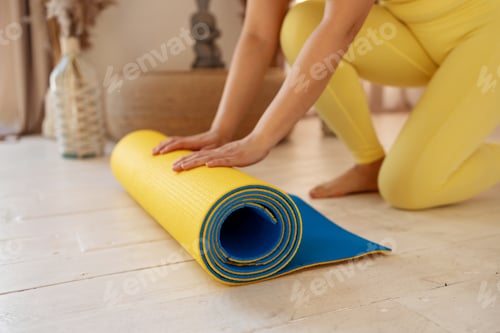 Preview: Yoga at home active lifestyle woman rolling exercise mat in living room for morning meditation yoga
