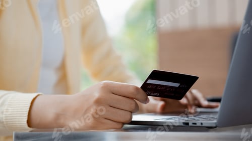 Preview: Woman holding a credit card, she uses a credit card to pay for goods and services online.