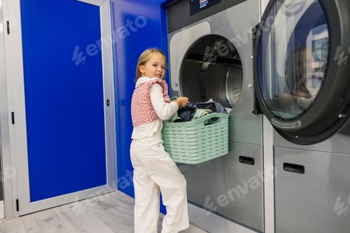 Preview: Young girl loading laundry into washing machine