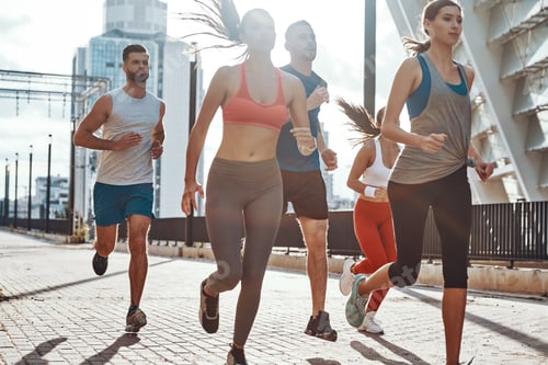 Preview: Group of young people in sports clothing jogging while exercising on the sidewalk outdoors