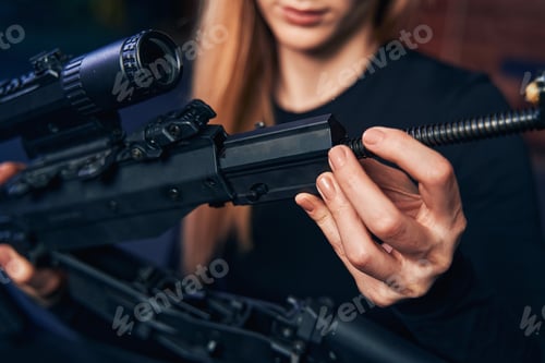 Preview: Experienced blonde female shooter assembling an assault rifle
