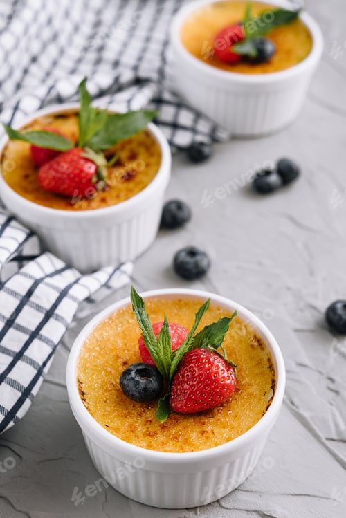 Preview: cup of creme brulee with dessert plug and mint leave with berries