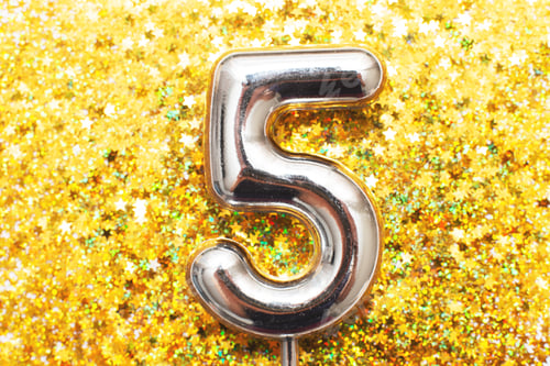 Preview: Five years birthday party. number five with golden confetti in form of stars on yellow background