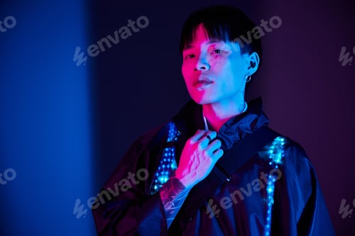 Preview: Stylish young asian man posing in vibrant lighting with a confident demeanor