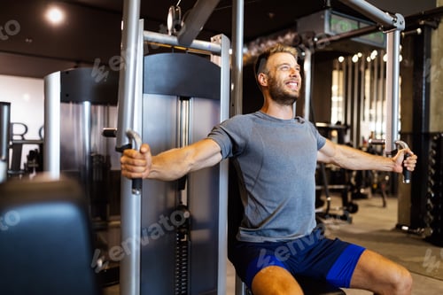 Preview: Young handsome man doing exercises in gym