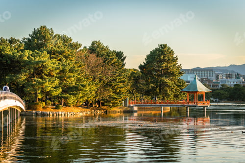 Preview: Scenic view of the pier at the Ohori park with a tranquil lake surrounded by lush green trees