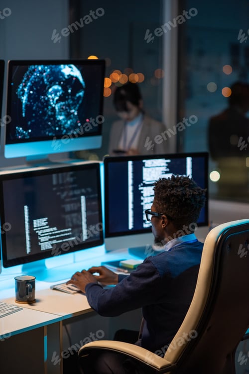 Preview: Young African developer sitting in armchair by desk
