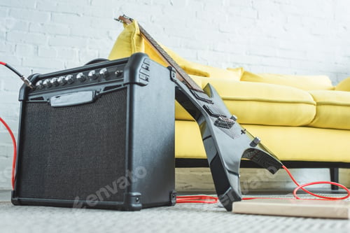 Preview: electric guitar and loud speaker standing on floor near sofa