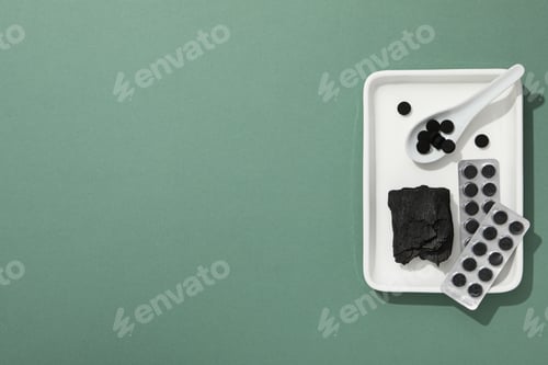 Preview: Activated charcoal tablets with a spoon in a white bowl