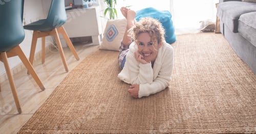 Preview: Portrait of smiling woman laying down at home on the natural carpet and looking on camera