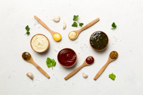 Preview: Different sauces in spoons on table background, flat lay top view