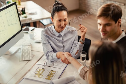 Preview: Happy Asian insurance agent shaking hands with her clients in the office.
