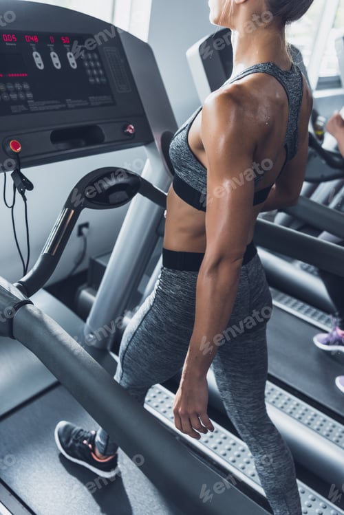Preview: selective focus of woman in sportswear exercising on treadmill in gym
