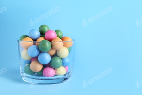 Preview: Bowl with bright gumballs on light blue background. Space for text