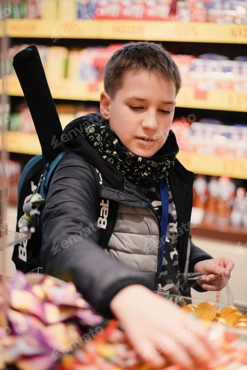Preview: Boy with a backpack grabbing candies in the sweets department store.