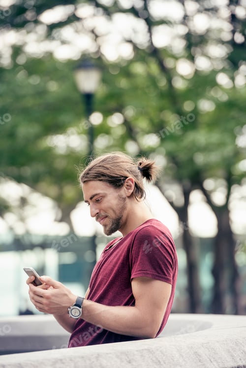Preview: A young man in a park checking his cell phone