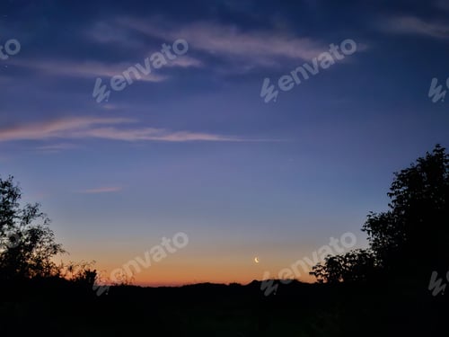 Preview: Serene sunset landscape with a crescent moon and silhouetted trees