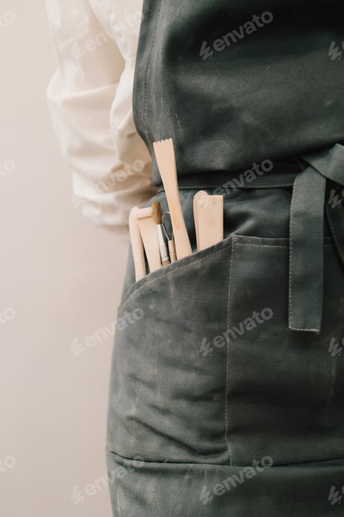 Preview: Assortment of pottery instruments. Artisan in black apron handling different tools