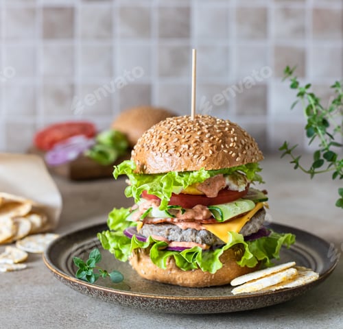 Preview: Tasty fresh homemade beef burger on ceramic plate with ingredients for making