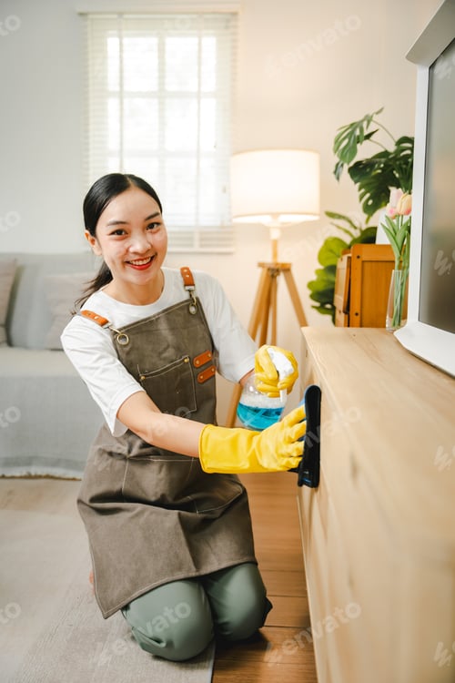 Preview: Young female housekeeper cleaning And wipe down the table with a microfiber cloth in the living room