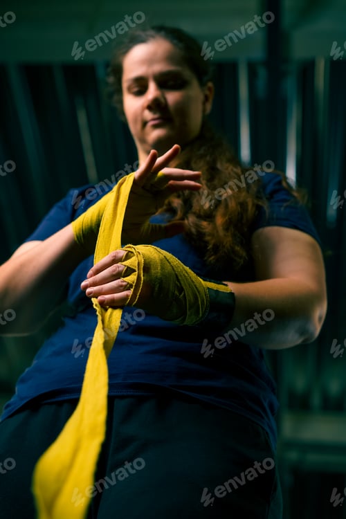 Preview: Sporty girl with strong arms prepares for a hard workout wraps a bandage on her fists