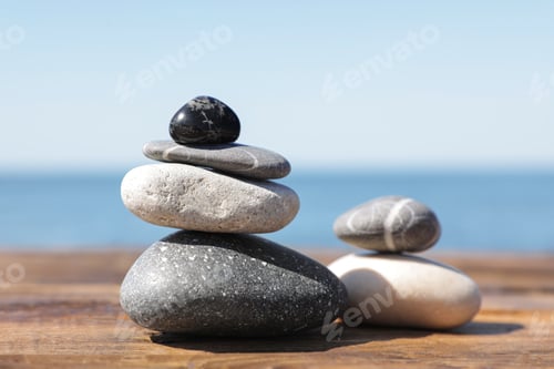 Preview: Stacks of stones on wooden pier near sea. Zen concept