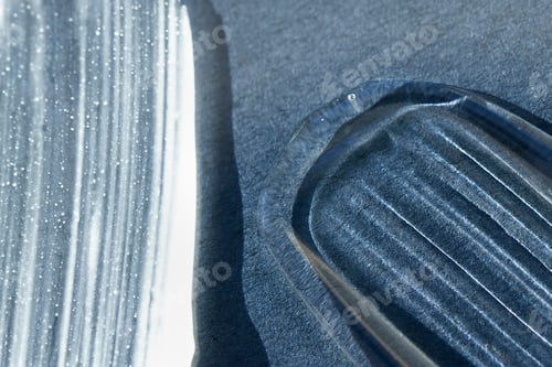 Preview: Smears of cosmetic textures in white and translucent color on a blue background, macro.